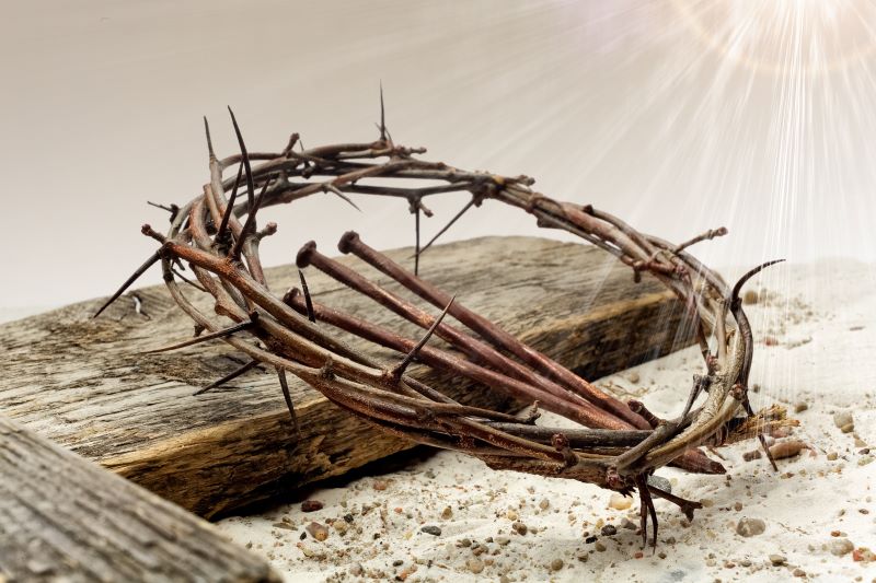 crown of thorns and nails laying on a wooden cross
